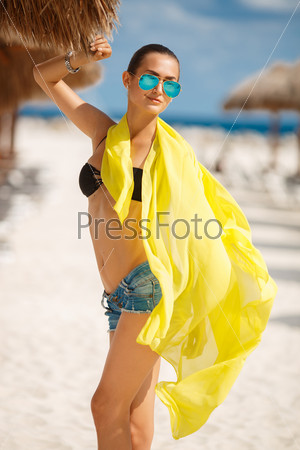 Beautiful sexy woman relaxing on the beach - outdoors. Young tanned woman on the beach in bikini and sunglasses. Young pretty hot sexy woman on the tropic island in summer near the sea