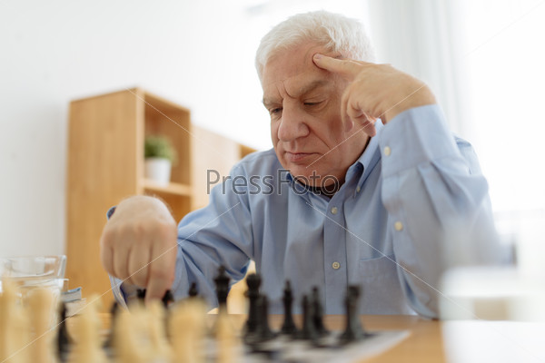 Senior man thinking over his move in chess