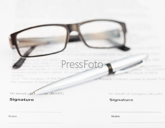 silver pen and eyeglasses on signature page of sales contract