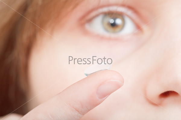 finger with corrective lens in front of face