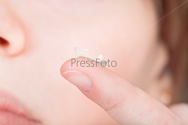 Contact lens on finger near female face