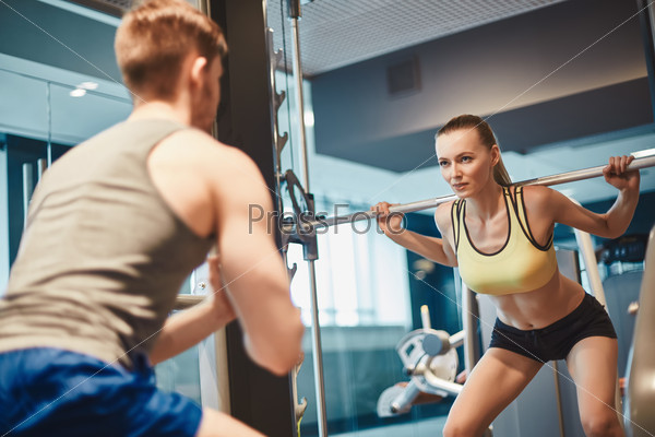 Active female looking at her trainer while lifting weight