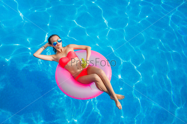 Sexy woman in bikini enjoying summer sun and tanning during holidays in pool with cocktail. Top view. Woman in swimming pool. Sexy woman in bikini.