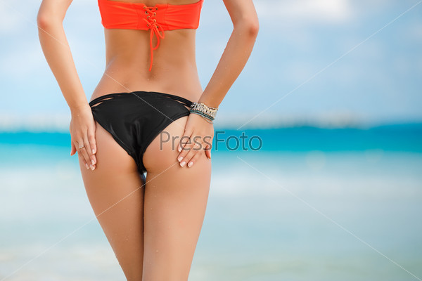 Sexy sandy woman buttocks on tropical beach background near ocean. close up outdoor shot of young woman in white bikini, sunbathing at sea shore. Black bikini