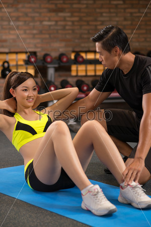 Young woman doing sit-ups in health club
