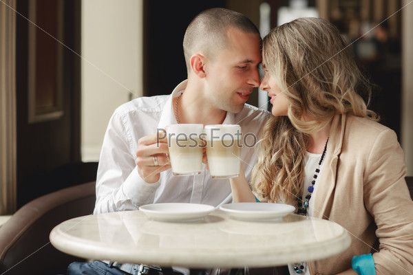 Happy man and woman in cafe. Loving couple on date at cafe. Two people in cafe enjoying the time spending with each other. Couple in cafe drinking coffee latte and smiling. Happy couple