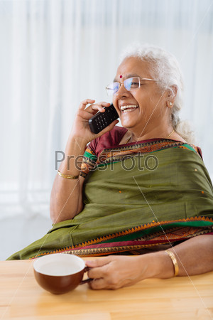 Happy mature Indian woman in sari talking on the phone