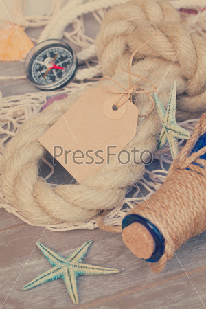 empty paper note with compass fishing net , marine rope and bottle, retro toned