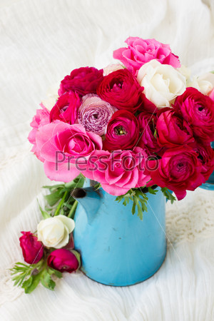 bunch of fresh pink  ranunculus and rose flowers  in blue pot