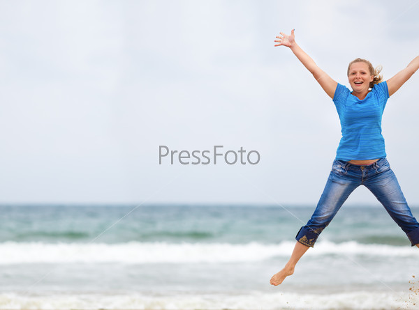 Happy woman jumping on the beach against the sea and cloudless sky. Selective focus. Space for text. Shallow depth of field. Focus on model.