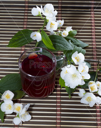 Glass of the red tea decorated with flower branches