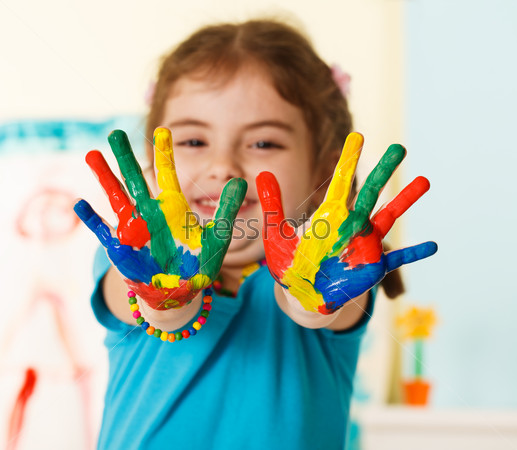 Five year old girl with hands painted in colorful paints ready for hand prints