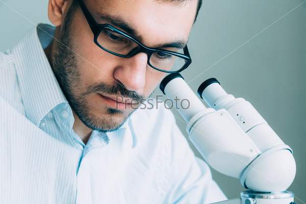 Closeup of young male doctor viewing through microscope