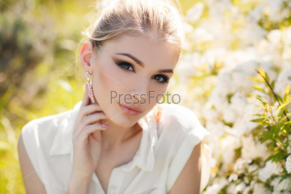 Blonde woman in flowers. beautiful happy blonde woman in the park on a warm summer day