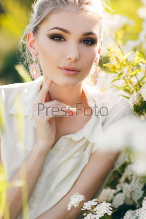 Blonde woman in flowers. beautiful happy blonde woman in the park on a warm summer day