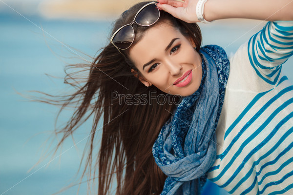 Brunette woman in sea style on the sea shore in spring time. Outdoor portrait of young sexy sensual sport woman posing on the sea in sunny weather and have fun in vacation time