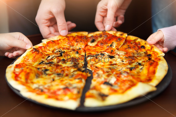 Hands of a big family taking pizza from plate