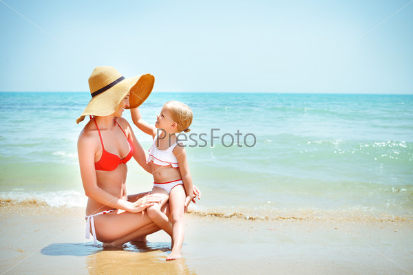 Happy mother and her baby daughter on sea coast. Summer holiday concapt