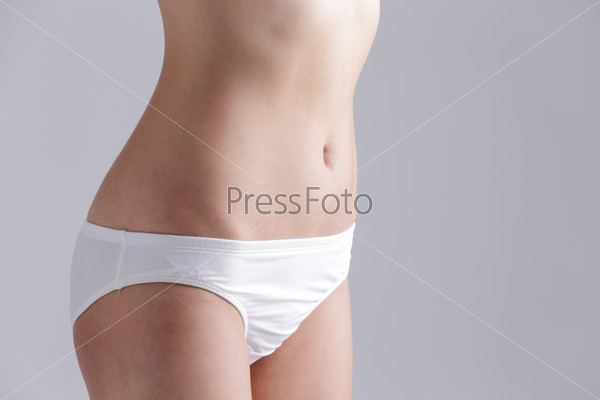 Beautiful slim woman body and sexy belly isolated on gray background