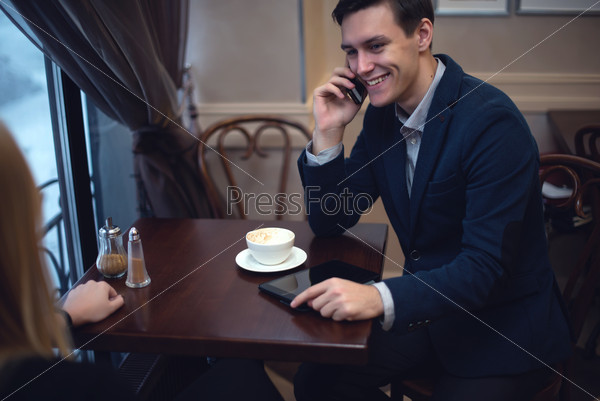 Handsome entrepreneur enjoying his launch in a cafe talking with someone by the phone