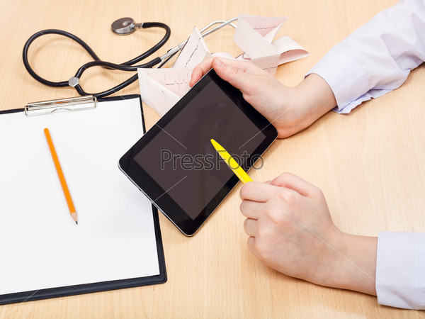 Doctor works with tablet pc during appointment, stock photo