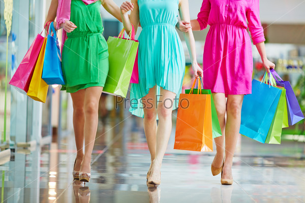 Group of shoppers in bright dresses walking in the mall