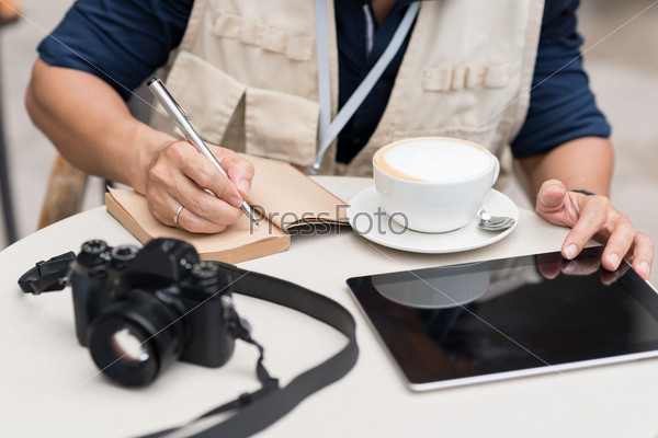 Cropped image of journalist making notes while sitting in the cafe