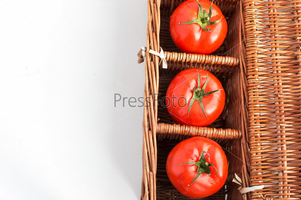Three tomatoes in wicker box with copy space