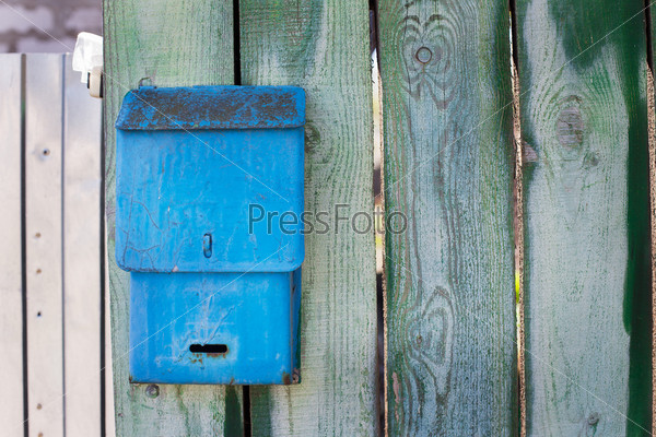 Blue mailbox on green fence