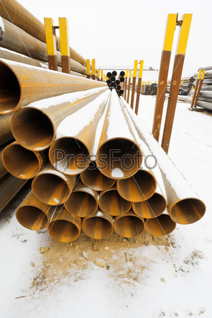 rusty steel pipes in stacks on outdoor warehouse in winter
