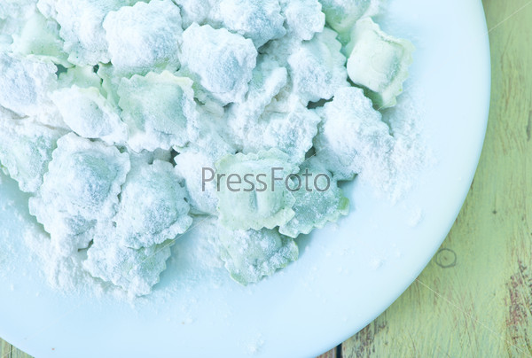 Flour and raw ravioli on a table, stock photo