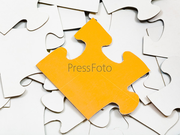 one yellow piece on pile of white jigsaw puzzles