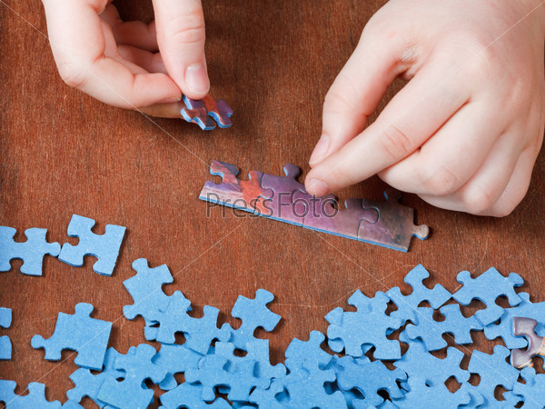 fitting of jigsaw puzzles on wooden table