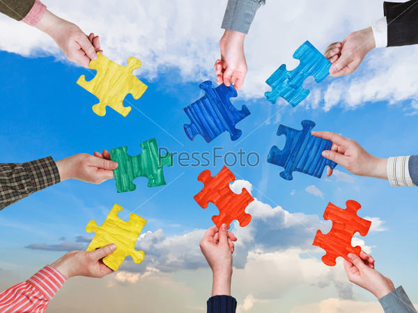 circle of people hands with different puzzle pieces with afternoon blue sky background