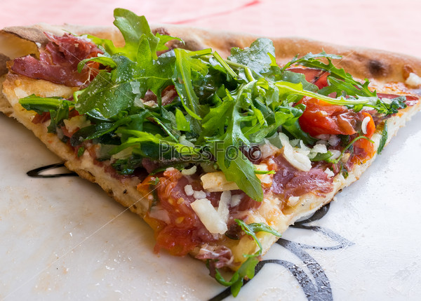 In the picture Italian pizza close-up with Arcula,cherry tomato,tomato,mozzarella,cheese,parmesan and Bresaola.