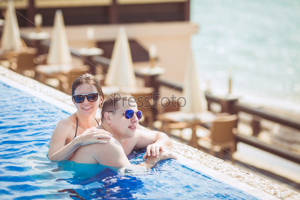 Young couple hugging in the pool in summer on tropical resort