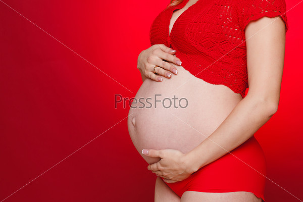 Pregnant Woman Belly. Pregnancy Concept. Isolated on a red Background