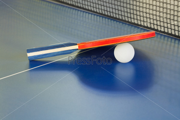 paddle, tennis ball on blue ping pong table close up
