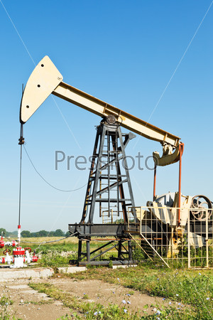 view of pumpjack pumping oil in summer day
