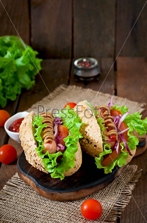 Hotdog with ketchup mustard and lettuce on wooden background