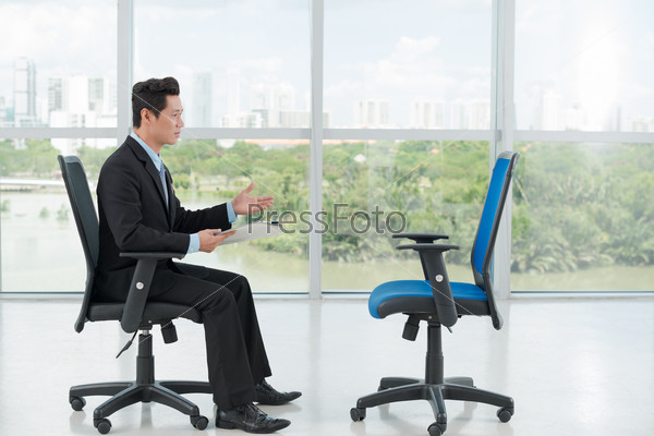 Employer interviewing an empty office chair, side view