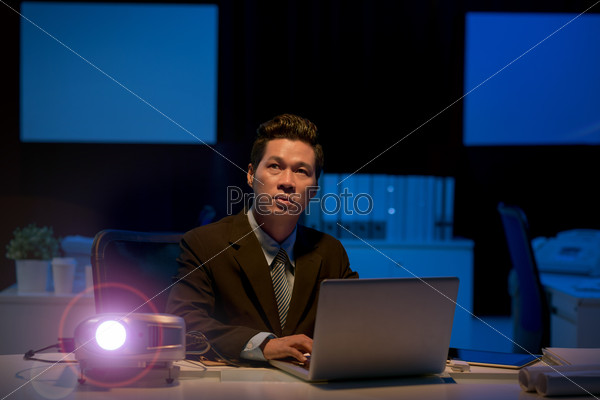 Businessman using projector while working on presentation in the office