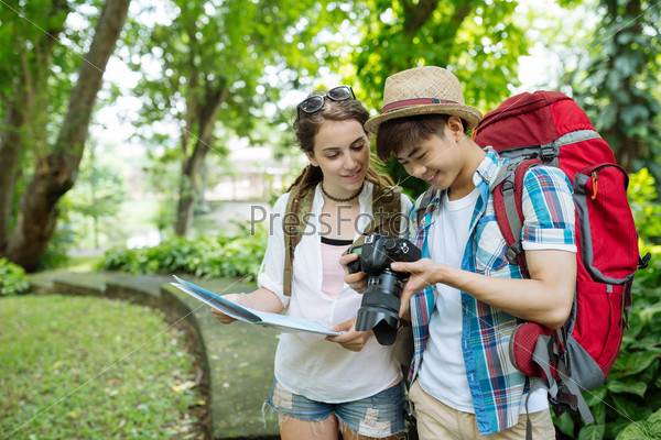 Multi-ethnic tourists looking at the photos on the screen of digital camera