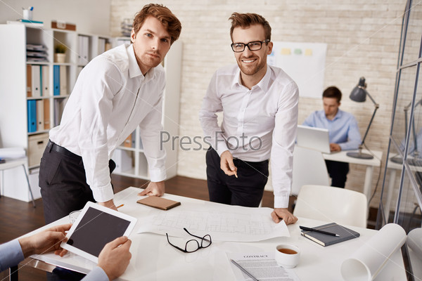 Elegant young architects looking at camera in working environment