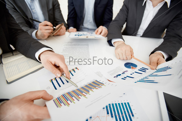 Two co-workers pointing at financial documents with data at meeting