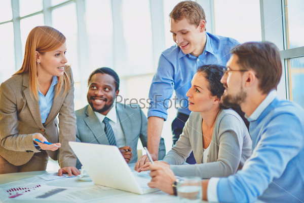 Group of employees looking at confident manager explaining her ideas at meeting