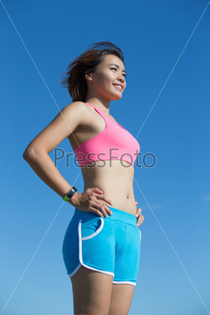 Health sport woman wearing smart watch device with touchscreen doing exercises with blue sky, asian beauty