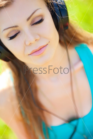 Beautiful young woman listen to music wearing headphones outdoors
