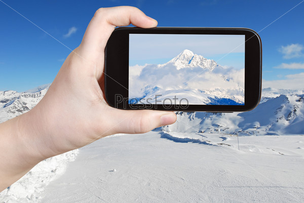 tourist taking photo of mountain peak in Alpes
