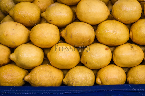 Pile of bright yellow lemons in fruit market, lemon background